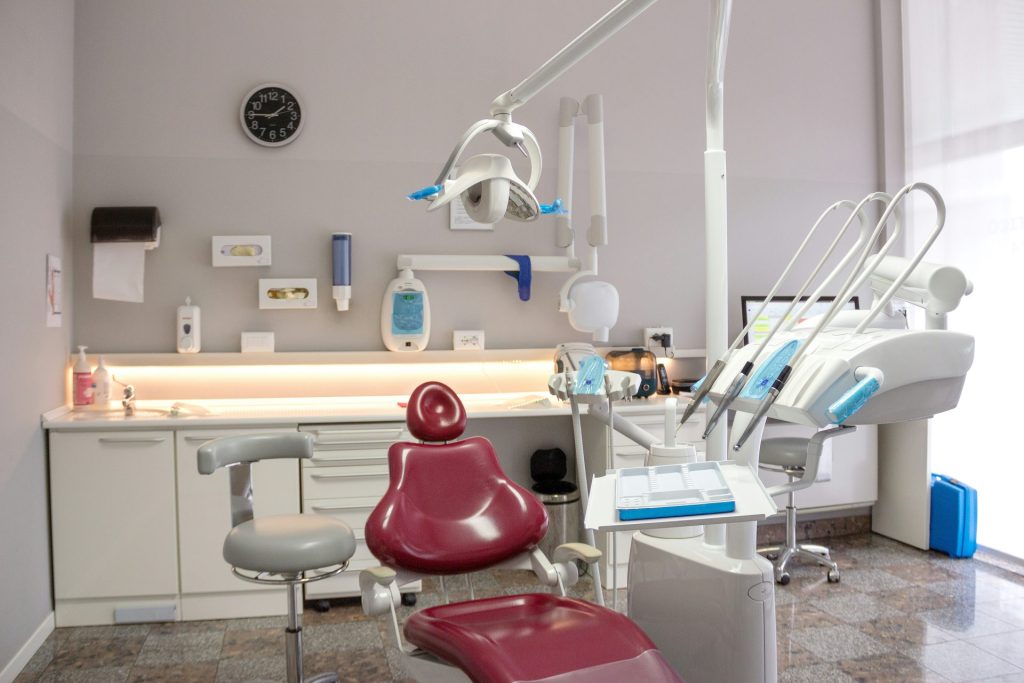 A dental room with a red chair and a sink