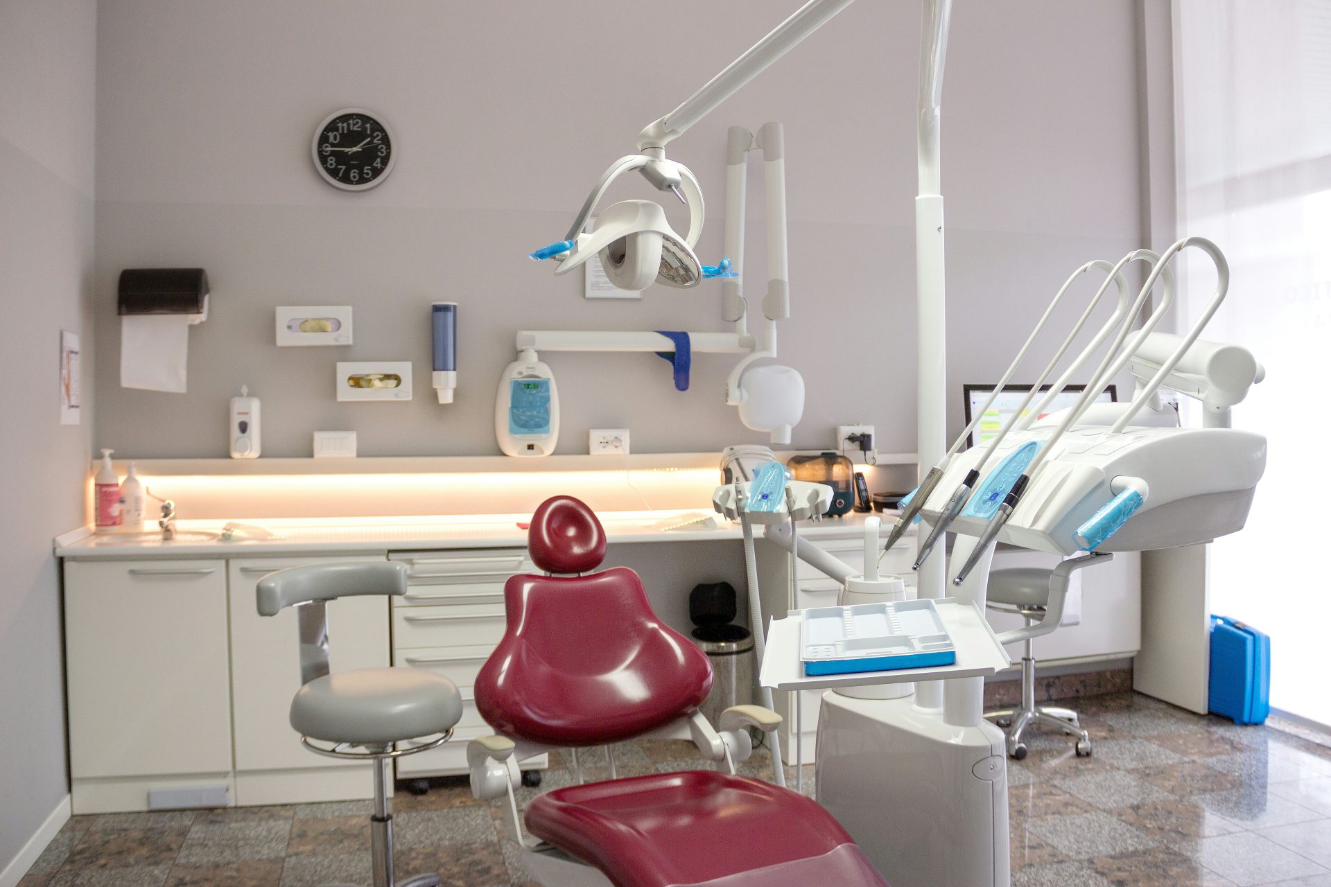 A dental room with a red chair and a sink